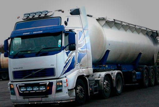 Silverfärgad Volvo-lastbil med en stor grå tanktrailer, fotograferad på en parkeringsplats.